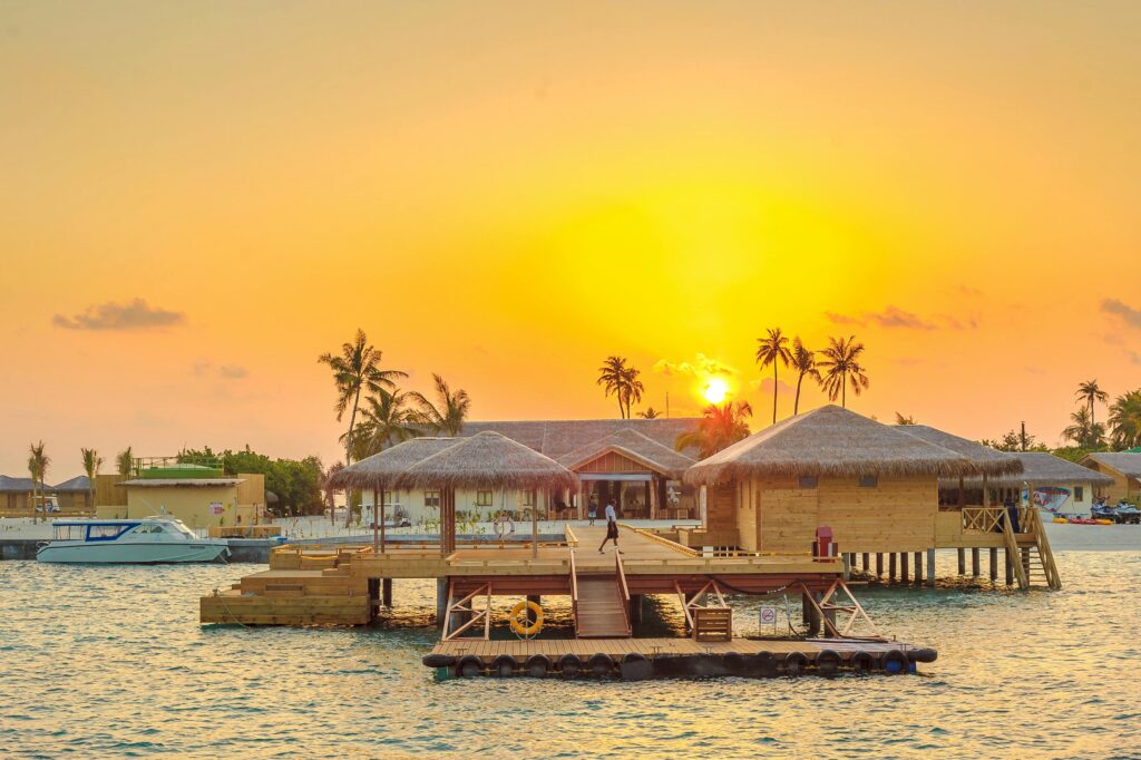 HOME Beautiful sunset view at Kanuhura, Maldives with overwater bungalows and serene ocean surroundings.