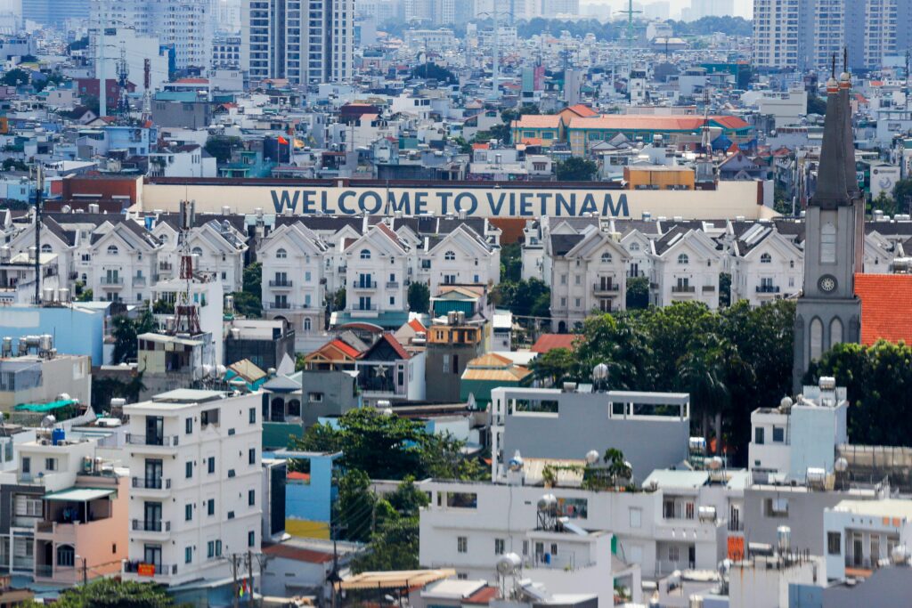 HOME A vibrant aerial view of Ho Chi Minh City featuring the iconic 'Welcome to Vietnam' sign among buildings.