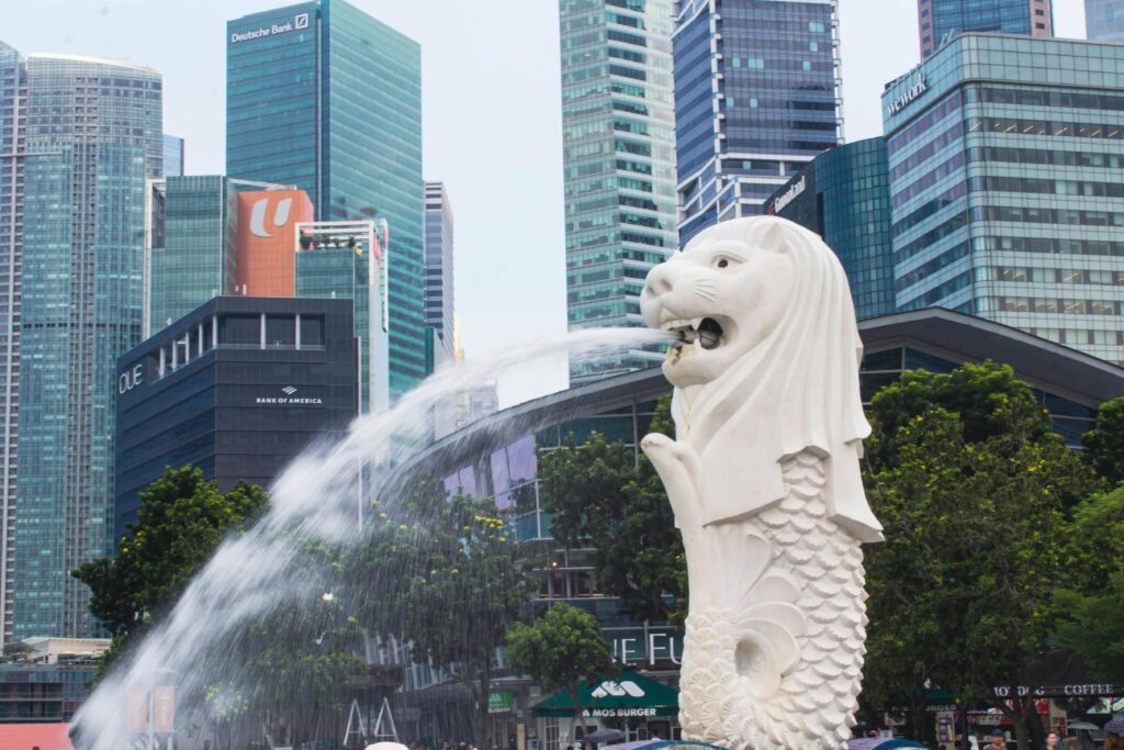 HOME The Merlion statue with flowing water in front of Singapore's modern cityscape.