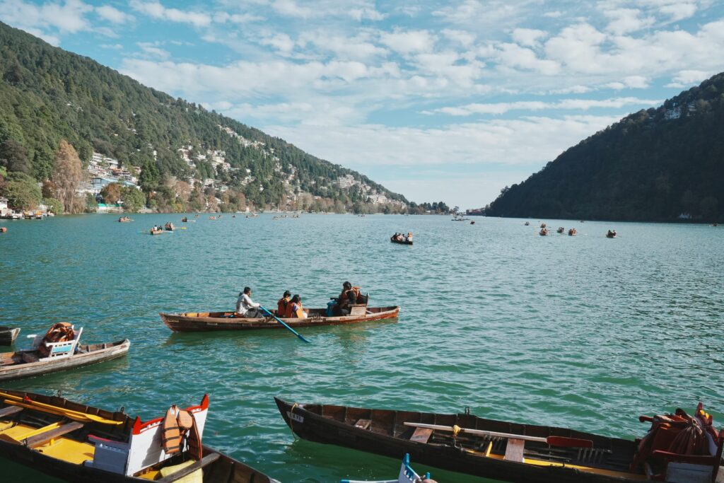 HOME Idyllic view of people boating on Nainital Lake with lush hills and clear skies.