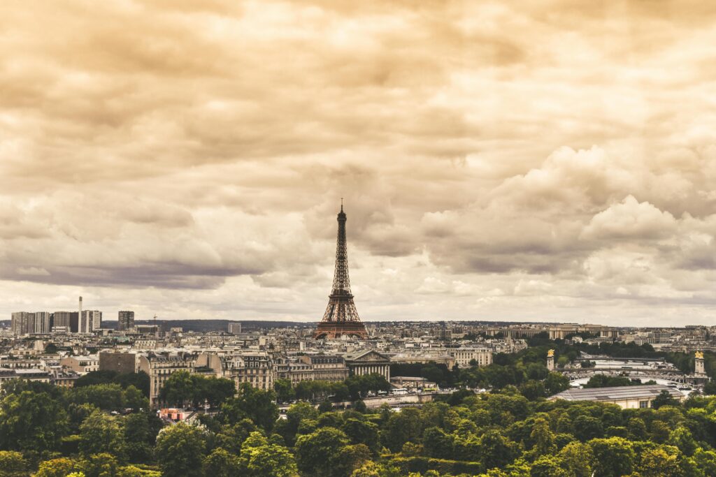 HOME The Eiffel Tower standing tall over Paris, under a dramatic cloudy sky.