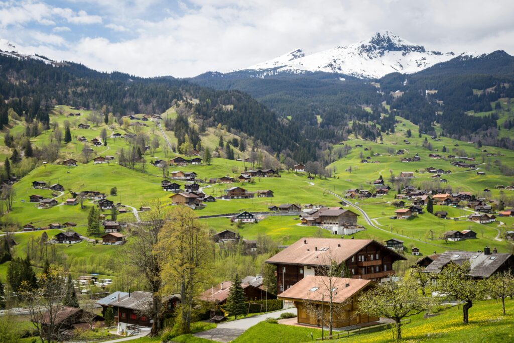 HOME Charming village surrounded by lush green hills and snowy mountains in Interlaken, Switzerland.