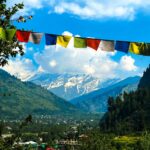 Charming view of Manali village with Himalayan mountains and colorful prayer flags in summer.