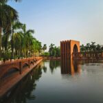 Peaceful scene of palm trees and architecture reflected in calm water.